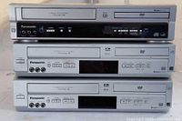 Three stacked Panasonic DVD/VHS combo units front view