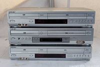 Three stacked silver Sony DVD VHS combo players front view