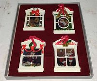 Four window-frame Santa ornaments in red tray