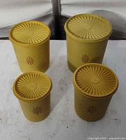 Four yellow Tupperware Servalier canisters with lids displayed together