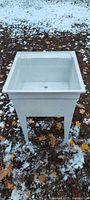 Front view of white freestanding utility sink standing outdoors
