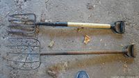 Both pitchforks laid side by side showing tines, shafts and D-grip handles