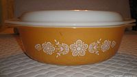 Side view of golden-yellow casserole showing white floral pattern and handles