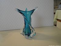 Front view of teal blue freeform glass vase with clear edging