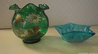 Green hand-painted ruffled glass bowl and blue star glass candleholder side view