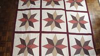 Full view of quilt showing star blocks and burgundy sashing