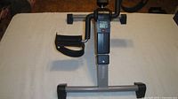 Full view of pedal exerciser showing frame, pedals, LCD screen and resistance knob