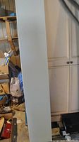 White particle board panel leaning against cabinets
