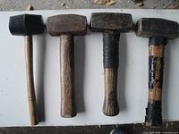 Front view of three sledge hammers and one rubber mallet lined up