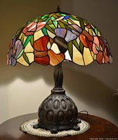 Front view of lamp showing entire floral stained glass shade and metal base