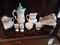 Overall view of coffee pot, creamer, sugar bowl, egg cups, teacup, toast rack