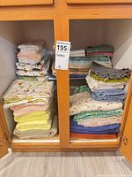 Cabinet interior showing stacked bath towels, hand towels, washcloths, dish towels and placemats