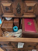 view into drawer showing multiple carved wooden boxes, turquoise glass dish, dreamcatcher, feathers, doily