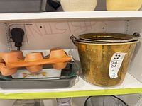 Shelf showing Pyrex dish, silicone muffin tray, and brass buckets