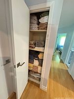 Tall linen closet with stacked towels, sheets and bath mat