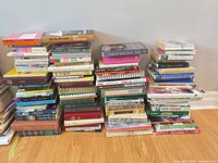 Multiple stacks of assorted books on hardwood floor