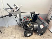 Full view of Briggs & Stratton S1024 snow blower showing controls, tires and chute