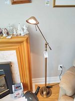 Full view of adjustable brushed brass floor lamp beside fireplace