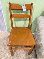 Front view of solid wood chair showing honey finish and surface wear