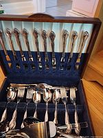 Open flatware case showing knives in lid and assorted pieces in tray