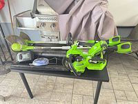 Overall lot view showing multiple Greenworks 40V tools, charger and accessories on table