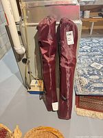 Two maroon folding camp chairs in bags leaning against furnace