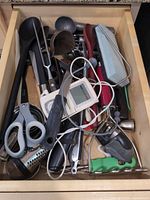 Drawer view showing assorted utensils including digital thermometer, scissors, grater, measuring cups, tongs
