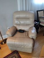 Front view of beige leather recliner with remote on seat
