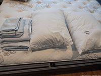 Folded sheet set beside two pillows on mattress