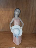 Front view of Lladró figurine girl in pink dress holding white hat