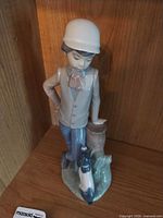 Front view of Lladro boy with dog porcelain figurine on shelf