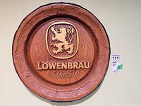 Full view of round wooden Löwenbräu plaque on wall