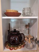 Cabinet view showing teapot, bowls, glassware, trivet, utensil holder with honey dippers