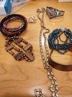 Overview of lot showing bangles, pearl bracelet, wood bracelet, chain necklace, seed bead bracelet, silver-tone cuff, copper cuff
