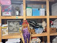 Overview of lot on shelving showing sombreros, wooden clogs, air mattress box, box fan, storage bins