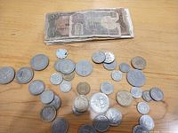 Stack of banknotes and spread of assorted coins on tabletop