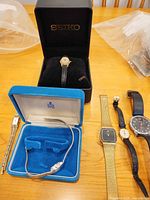 Overall view of lot showing Seiko boxed watch, Birks box with silver watch, additional watches lined up
