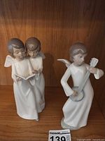 Both NAO angel musician figurines on shelf