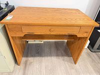 Front view of oak finish desk showing drawer and lower shelf