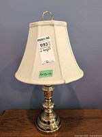 Single brass-tone table lamp with shade showing overall design