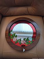 Front view of round wood framed mirror with stained glass floral border