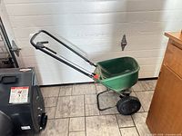 Side view of Scotts broadcast spreader with green hopper and black wheels