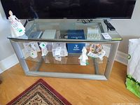 Front view of silver metal TV stand with three glass shelves