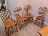 Four spindle-back chairs in a row showing fronts and seat surfaces