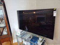 Front view of Sony 55-inch TV on glass stand with remote visible