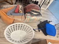 overall lot showing throw pillows in plastic bags, laundry basket, seat cushions