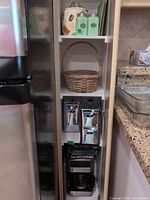 Narrow shelving with green jars, wicker basket, stainless canisters, coffee maker