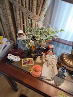 Overall lot showing dolls, figurines, tile, pottery bowl and faux ivy