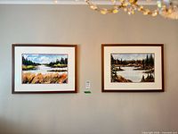 Both framed watercolor landscapes hanging side by side on wall