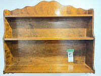 Front view of brown two-tier wall shelf showing overall design and scalloped top